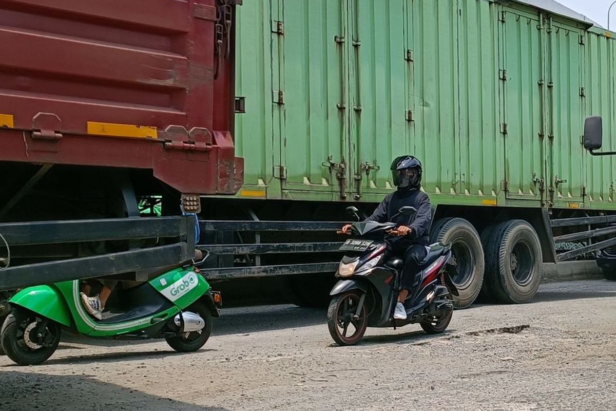 Ilustrasi pesepeda motor mendahului kendaraan besar.