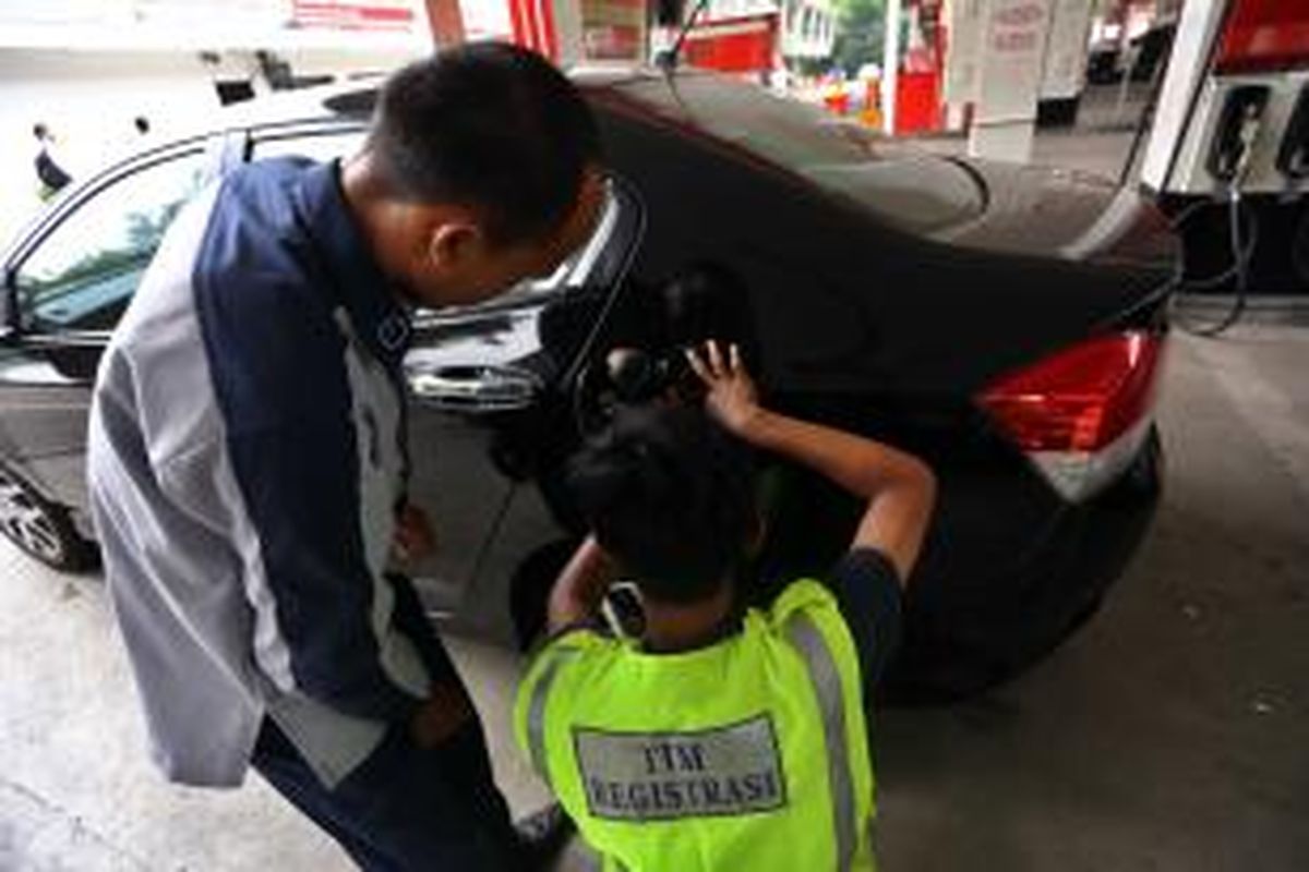 Petugas memasang cincin Radio Frequency Identification (RFID) kepada salah satu mobil mewah di SPBU kawasan Tanah Abang, Jakarta Pusat, Selasa (3/12/2013). 