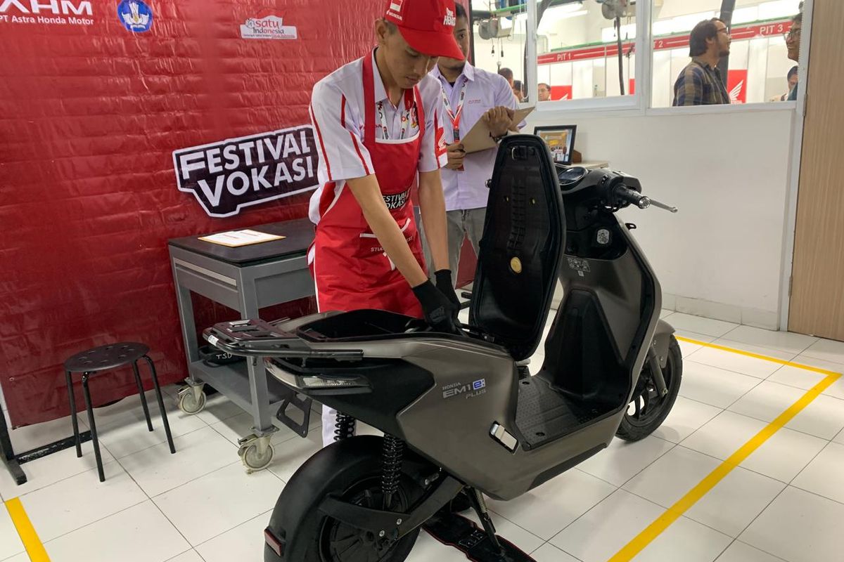 Seorang teknisi sedang mencabut baterai motor listrik Honda EM1 e: Plus