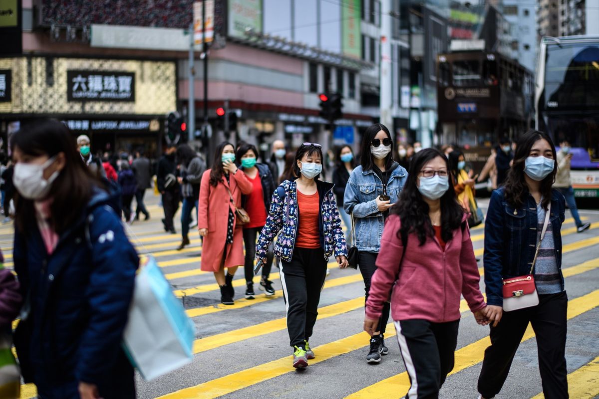 Pengguna jalan mengenakan masker melintas di jalanan Hong Kong di tengah masa liburan Tahun Baru Imlek pada 27 Januari 2020. Saat ini, China tengah dihantam virus corona yang sudah membunuh lebih dari 100 orang.
