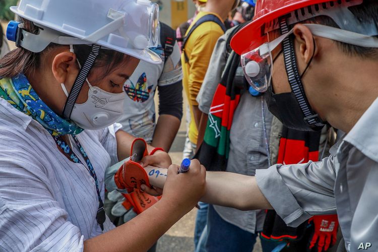 An anti-coup protester writes emergency information of another protester on his arm in Yangon, Myanmar, (3/3/2021)