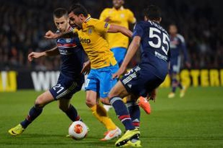 Striker Juventus, Carlos Tevez, saat berusaha melewati dua pemain Lyon pada leg pertama perempat final Liga Europa di Stade de Gerland, Kamis atau Jumat (4/4/2014) dini hari WIB. 