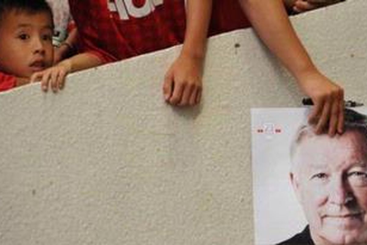 Seorang suporter memegang foto Manajer Manchester United, Sir Alex Ferguson di Stadion Shanghai, menyambut kehadiran klub itu pada 24 Juli lalu. Ferguson sedang dikritik fansnya, karena mendukung pemilik klub menjual sebagian saham klub.