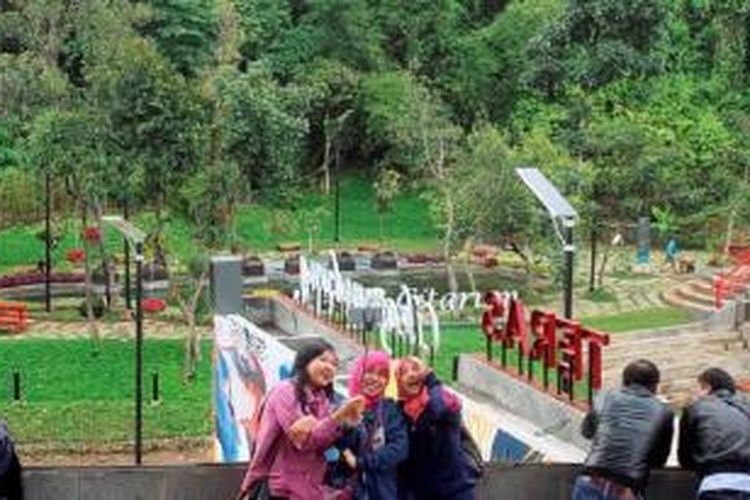 Pengunjung berfoto dengan latar belakang Teras Cikapundung, Kota Bandung, Minggu (10/1). Taman kota menjadi tempat favorit bagi warga Bandung pada akhir pekan.
