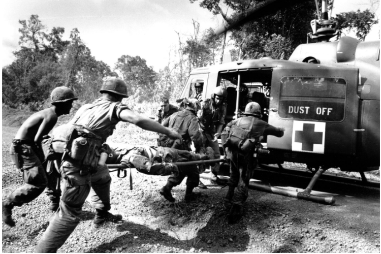 Perang Vietnam: Pasukan terjun payung AS membawa seorang tentara yang terluka ke helikopter ambulans selama Perang Vietnam, 1965.