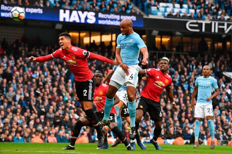 Vincent Kompany unggul dalam duel udara melawan Chris Smalling pada laga Derbi Manchester antara Manchester City dan Manchester United di Stadion Etihad, Sabtu (7/4/2018). 