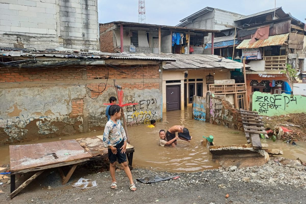 Anak-anak di RT 02/RW 07, Kelurahan Rawajati, Pancoran, Jakarta Selatan, yang bermain air genangan banjir, Minggu (5/11/2023) pagi.