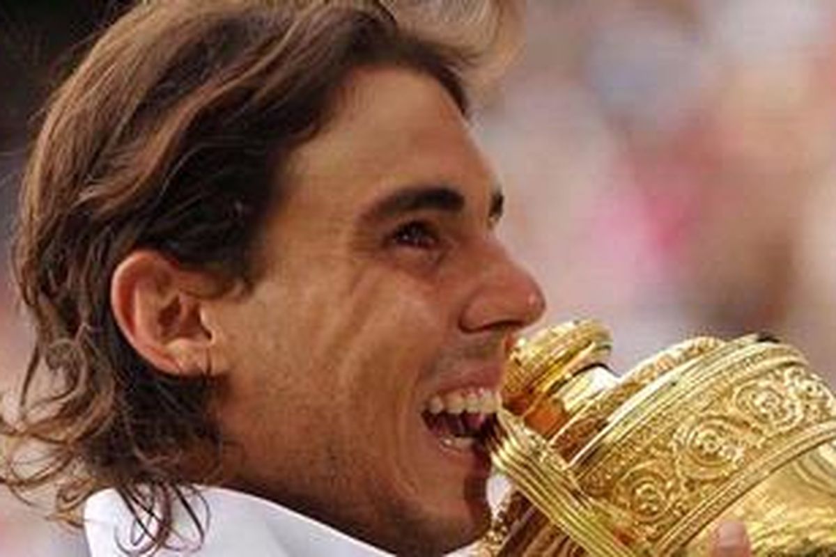 Rafael Nadal menggigit trofi Wimbledon 2010.