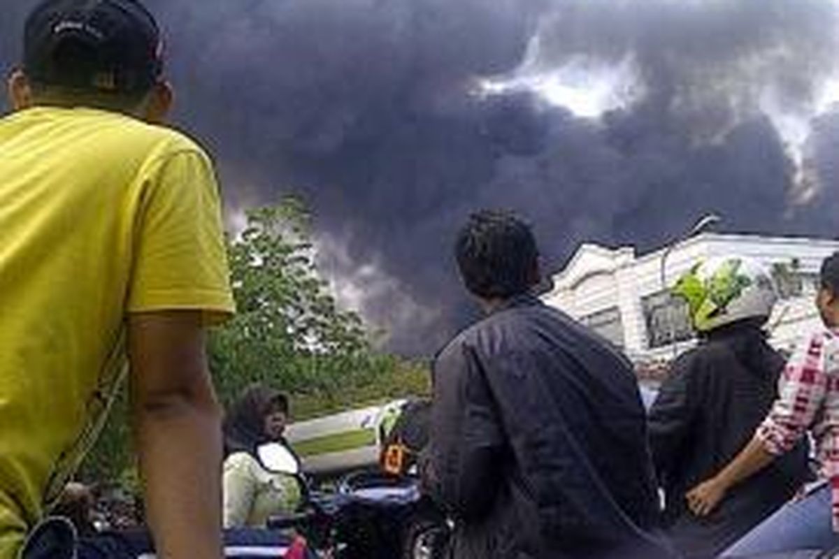 Warga berdiri di pinggir jalan menyaksikan kebakaran yang terjadi di areal PT Bina Karya Prima, Bekasi, Jumat (24/10/2014).
