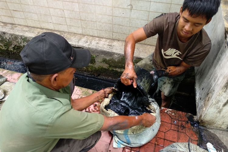 Pekerja kebersihan sedang melakukan pembersihan saluran air dari lumpur di RT 02 RW 08 Kelurahan Sunter Jaya, Selasa (21/11/2017). Sebelumnya wilayah ini mendapat sorotan karena pengurus RT 02 menyebarkan edaran untuk dana iuran kebersihan dan menjadi viral di media sosial.