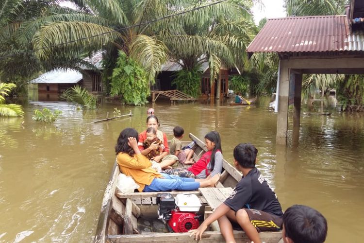 Warga korban banjir di Desa Buluh Cina, Kecamatan Siak Hulu, Kabupaten Kampar, Riau, menggunakan perahu mesin untuk pergi mengungsi, Senin (17/12/2018).