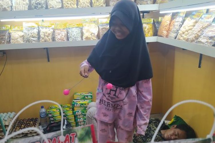 Seorang anak perempuan penjaga toko oleh-oleh di Rest Area Banjaratma, Brebes, Jawa Tengah memainkan lato-lato menjelang tahun baru 2023.