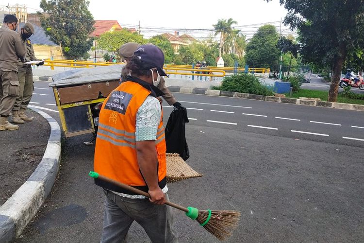 Salah satu warga yang melanggar aturan PSBB menjalani kerja sosial dengan menyapu jalanan sambil memakai rompi pada Kamis (14/5/2020) 
