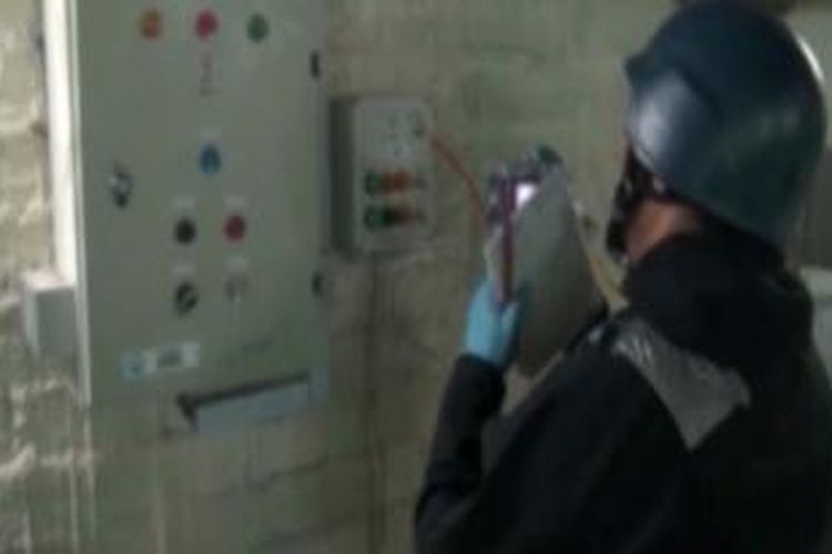 Gambar yang diambil dari siaran televisi pemerintah Suriah ini menampilkan salah seorangn petugas OPCW tengah bekerja di salah satu lokasi penyimpanan senjata kimia Suriah. Selama 10 hari terakhir tim OPCW sudah mendatangi tiga lokasi penyimpanan senjata kimia.