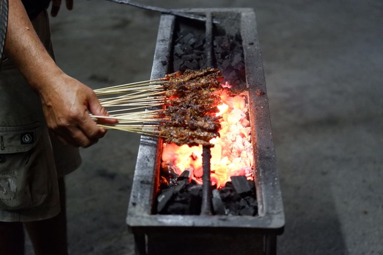 Ilustrasi sate dibakar menggunakan arang. 