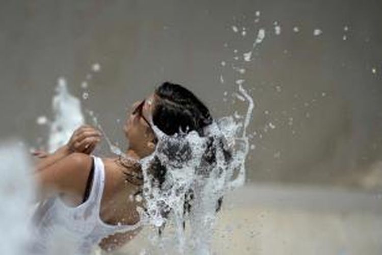 Seorang turis mendinginkan tubuh di air mancur Ara Pacis di Roma, 27 Juli 2013. Temperatur di Roma, Naples, Florence dan Bologna mencapai 42 derajat Celsius.