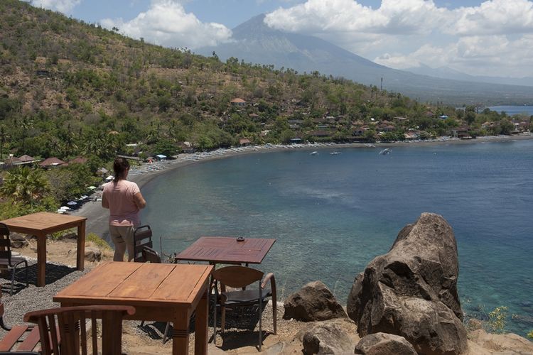 Seorang wisatawan menikmati pemandangan di Pantai Desa Amed, Karangasem, Bali, Jumat (29/9/2017). Status Gunung Agung yang mengalami peningkatan dari level III (Siaga) menjadi level IV (Awas) tak berdampak signifikan terhadap kunjungan sejumlah destinasi wisata di Bali yang tetap ramai pengunjung.