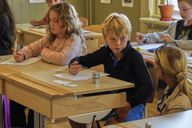 Seorang guru membantu siswa mempraktikkan tulisan tangan mereka di sekolah dasar Djurgardsskolan di Stockholm, Swedia, Kamis, 31 Agustus 2023.