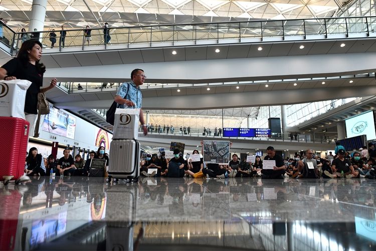Massa unjuk rasa berkumpul di gerbang kedatangan internasional di bandara Hong Kong, Jumat (26/7/2019).
