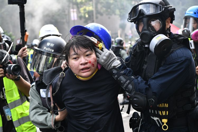 Seorang demonstran ditahan oleh polisi dekat Polytechnic University di distrik Hung Hom, Hong Kong, pada 18 November 2019. Massa pro-demokrasi menduduki kampus tersebut dalam tiga hari terakhir, dan memberikan perlawanan kepada polisi yang mengepungnya.