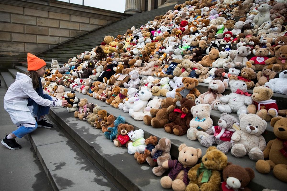 Seorang anak membantu menyusun boneka Teddy Bear di tangga di depan Balai Konser di Berlin, Kamis (15/3/2018).