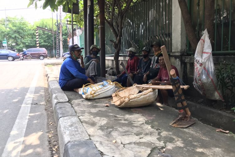 Para tukang gali harian sedang duduk menunggu pengguna jasa mereka di pinggir selokan Jalan Adhyaksa Raya, Lebak Bulus, Cilandak, Jakarta pada Rabu (28/10/2020) siang. Para tukang gali harian ini mayoritas berasal dari Brebes, Jawa Tengah dan sudah mengadu nasib di Jakarta selama puluhan tahun.