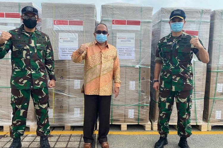 Duta Besar Indonesia untuk Singapura Suryo Pratomo (tengah) berfoto di depan bantuan masker Covid-19 yang diserahkan oleh Yayasan Temasek Singapura untuk diangkut ke Pelabuhan Tanjung Priok, Jakarta, Kamis (25/02/2021)