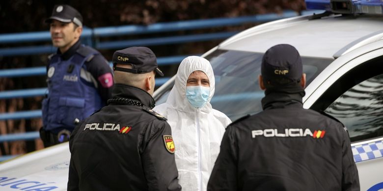 Seorang anggota dari militer Spanyol berbicara dengan dua polisi di Madrid, pada 24 Maret 2020, di tengah wabah virus corona.