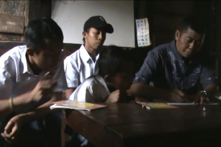 MENGAJAR--Edi Gunarso, seorang guru di Kabupaten Madiun terpaksa memberikan pelajaran bagi tiga siswanya di rumah penduduk karena atap SDN Kare 7 ambrol.