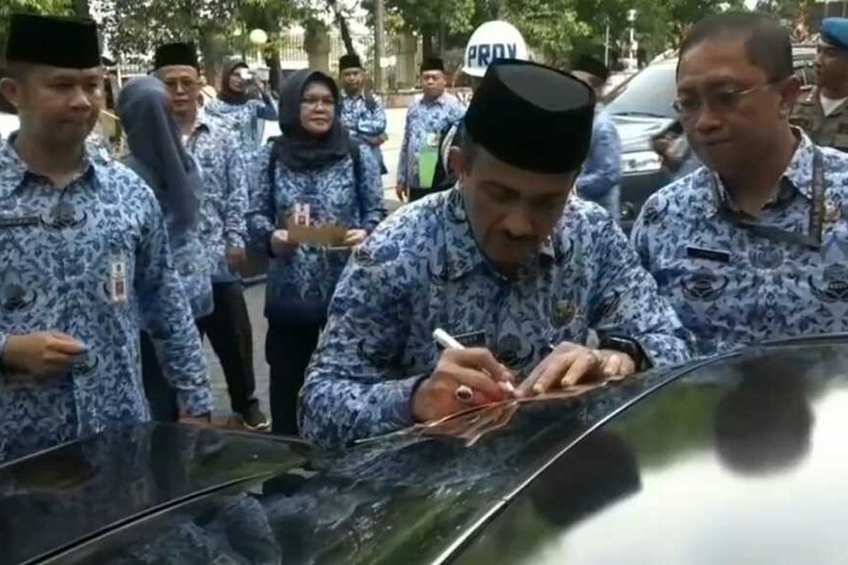 Wali Kota Jakarta Timur M Anwar saat menempel mobil milik Aparatur Sipil Negara (ASN) Pemkot Jakarta Timur di Halaman Parkir Kantor Wali Kota Jakarta Timur, yang masih menunggak pajak kendaraannya, Minggu (23/12/2019).