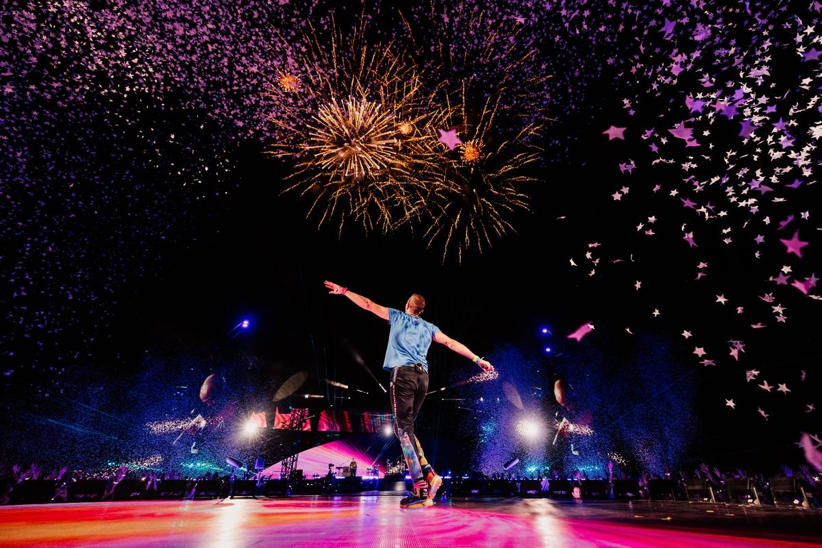 Vokalis grup band Coldplay tengah menikmati energi dari atas panggung dalam tur Coldplay Music of the Spheres World Tour 2023.