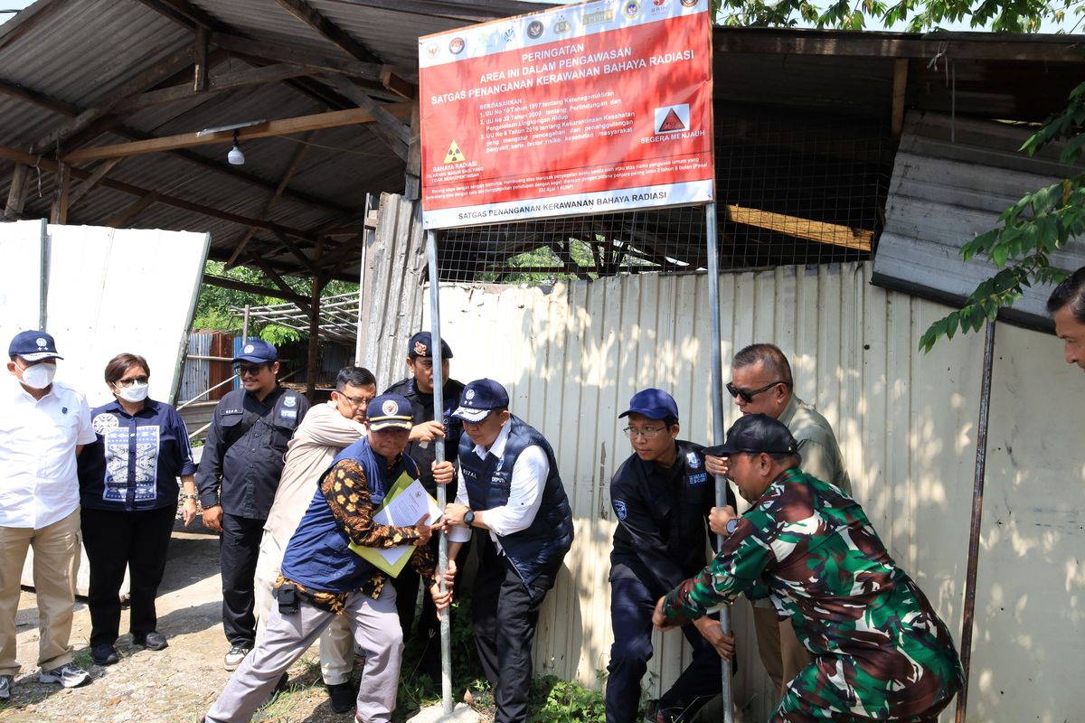 Petugas melepaskan plang penyegelan di pabrik Cikande yang sebelumnya terpapar radioaktif. 