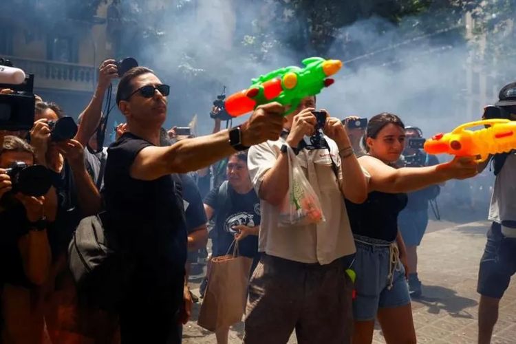 Aksi demonstrasi tolak pariwisata massal di Barcelona, Spanyol, Minggu (15/6/2025). Para peserta aksi menembakkan pistol air ke toko-toko di sekitar lokasi.