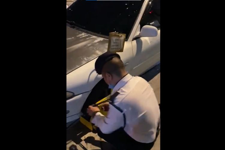 Tangkapan layar dari video mobil yang diduga parkir sembarangan lalu dicoreti pakai spidol dan digembok bannya di Malaysia.