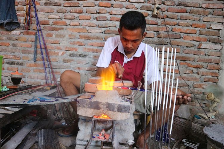 Para pekerja di tempat produksi manik-manik milik Suloso, di Desa Plumbon Gambang, Kecamatan Gudo, Kabupaten Jombang, Jawa Timur, sedang memproses bahan dasar manik-manik menjadi butiran perhiasan.