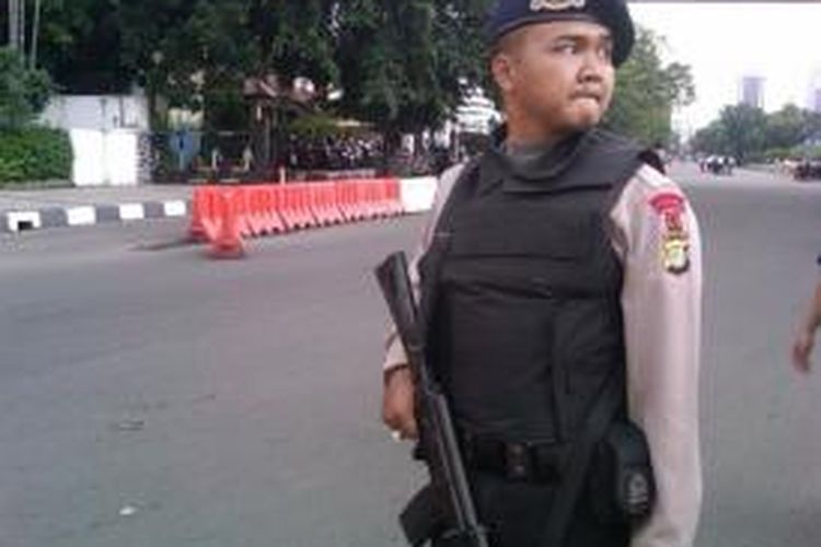 Seorang anggota Brimob Polri berjaga di sekitar tempat penemuan koper abu-abu mencurigakan di samping Kedubes AS, Jalan Merdeka Selatan, Gambir, Jakarta Pusat, Kamis (5/12/2013) sore. 