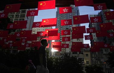 FILE - Seorang pria berjalan melewati bendera China dan Hong Kong untuk merayakan peringatan 25 tahun penyerahan Hong Kong ke China, di Hong Kong, Jumat, 24 Juni 2022.
