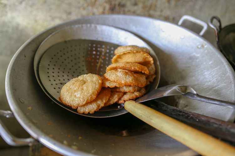 ilustrasi kue cucur yang sedang ditiriskan. 