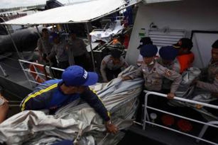 Anggota Kapal Polisi Punai, menurunkan serpihan dari pesawat AirAsia QZ8501di Pelabuhan Kumai, Kalimantan Tengah, Kamis (1/1/2015). Serpihan ini ditemukan oleh kapal Malaysia yang turut serta dalam pencarian dan kemudian dipindahkan ke kapal polisi.