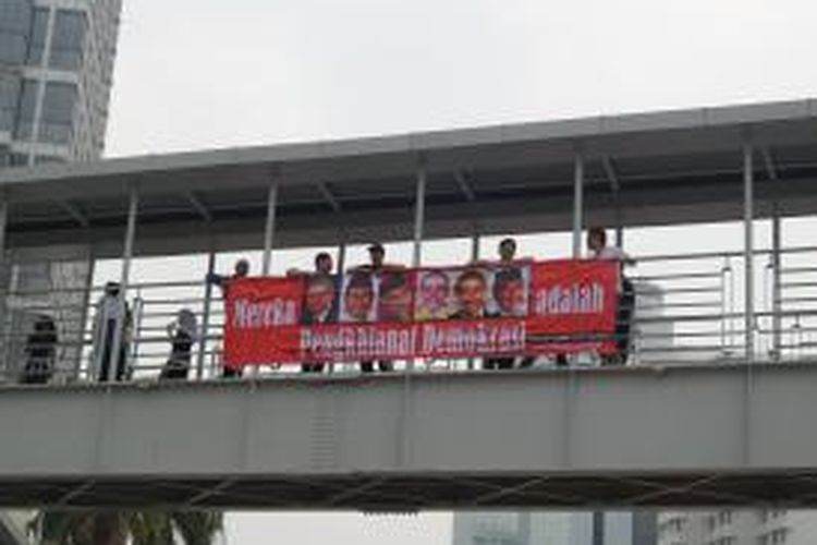 Spanduk bergambar Presiden Susilo Bambang Yudhoyono beserta tokoh-tokoh dari Koalisi Merah Putih yang diberi tanda silang, dipasang para pengunjuk rasa anti Pilkada Tak Langsung di jembatan penyebrangan, di kawasan Bundaran HI, Minggu (28/9/2014) pagi 