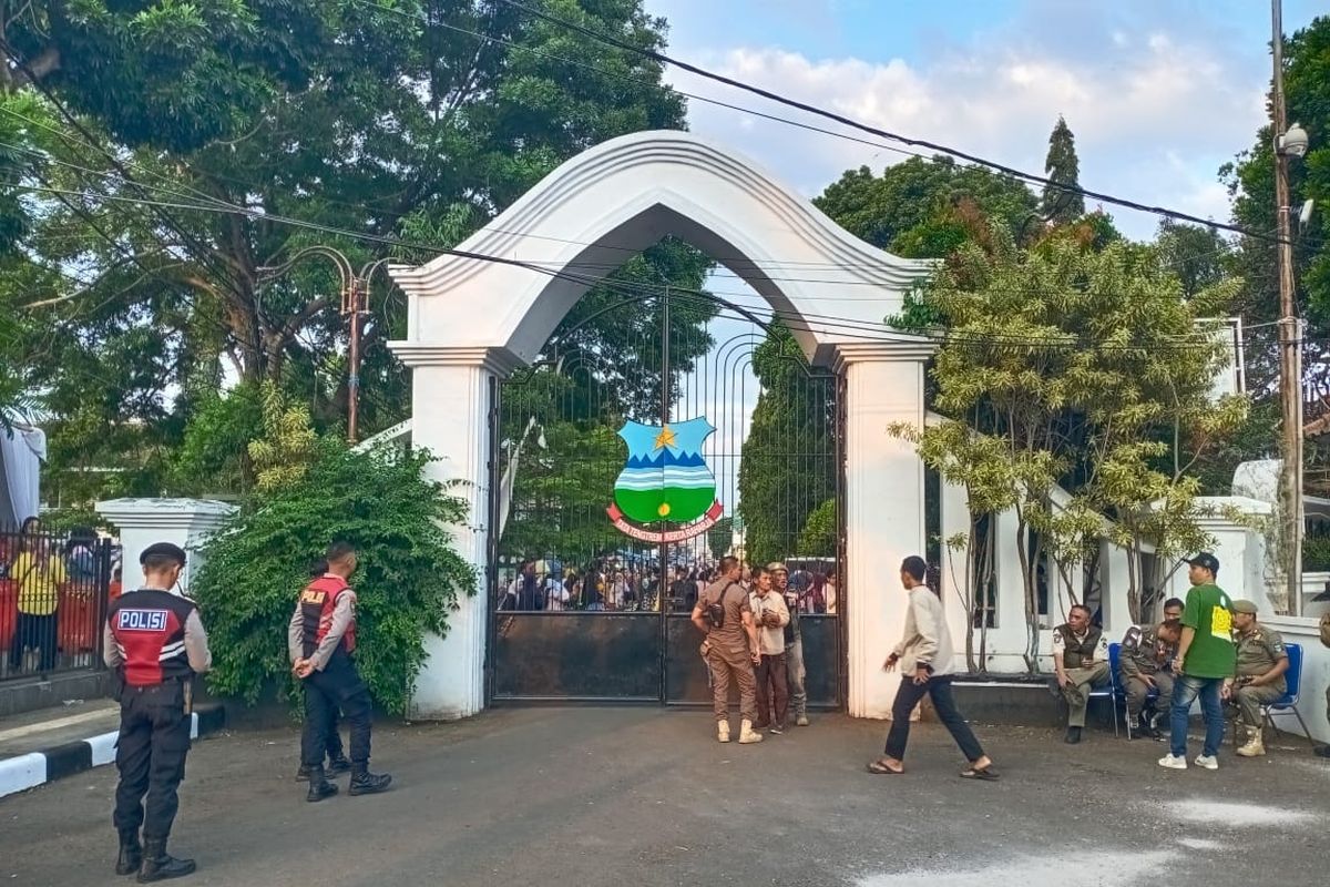 Gerbang Timur Pendopo Garut, Jawa Barat, Jumat (18/7/2025). Sejumlah aparat kepolisian dan Satpol PP berjaga usai insiden sejumlah warga tewas usai mengantre makanan di Pesta Rakyat yang merupakan rangkaian pernikahan Maula Akbar, putra dari Gubernur Jabar Dedi Mulyadi dan Wakil Bupati Garut Putri Karlina.