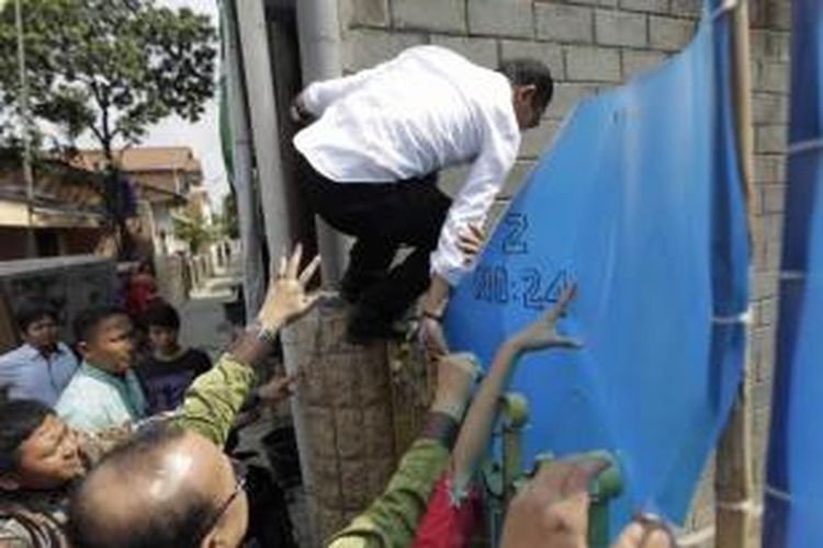 Menteri Ketenagakerjaan Hanif Dhakiri melompati pagar saat melakukan inspeksi mendadak di Perusahaan Pengerah Tenaga Kerja Indonesia Swasta (PPTKIS) Elkari Makmur Sentosa yang terletak di Jalan Asem Baris Raya, Gang Z, Tebet, Jakarta Selatan, Rabu (5/11/2014). Dalam sidak kali ini Menaker menemukan sejumlah pelanggaran di antara lain tempat tidur yang tidak layak dan penampungan yang tertutup.