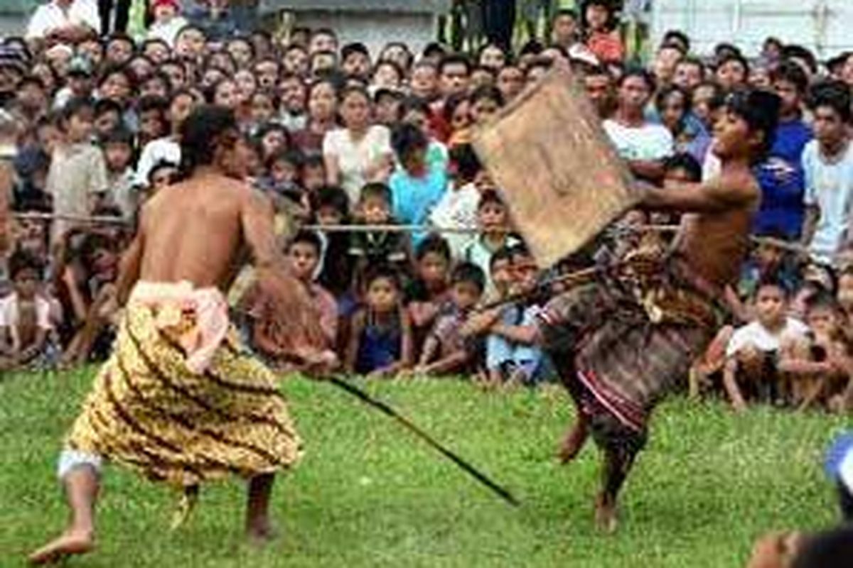 Dua pepadu saling serang di lapangan rumput depan Kecamatan Labu Api, Lombok Barat, NTB. Dahulu tarung perisean hanya dimainkan di persawahan sebagai ritual untuk meminta hujan.