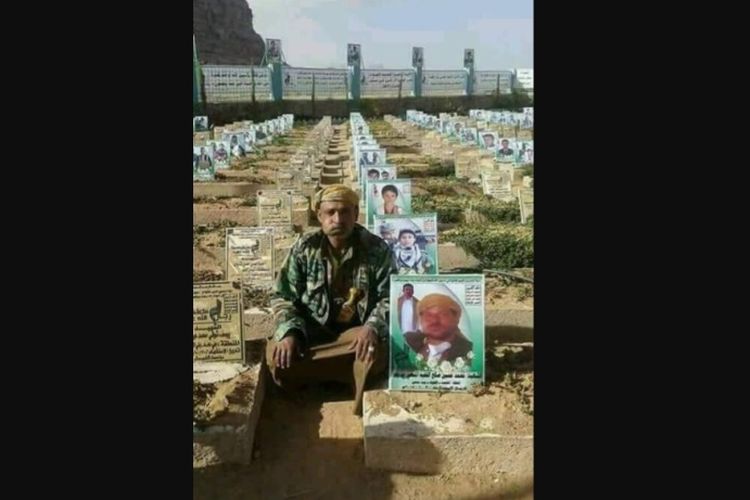 Mohammed Hussein Saleh yang membelot dari kelompok milisi Houthi berfoto di samping makamnya.