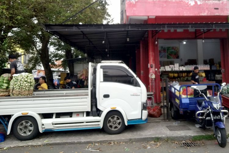 Seorang pekerja menurunkan sayuran dari bak mobil pikap putih di depan sebuah toko sayuran dan bumbu dapur di Jalan Kacapiring, Kota Blitar, Senin (6/4/2026)