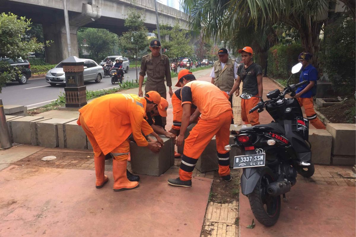 Petugas Penanganan Prasarana dan Saran Umum (PPSU) dan Satpol PP Kelurahan Menteng Atas, Jakarta Selatan merapikan beton pembatas yang dibongkar pengendara sepeda motor di depan TPU Menteng Pulo, Rabu (7/11/2018).