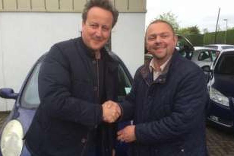 PM Inggris David Cameron (kiri) bersalaman dengan Iain Harris, pemilik showroom, tempat dia membeli mobil bekas untuk sang istri.