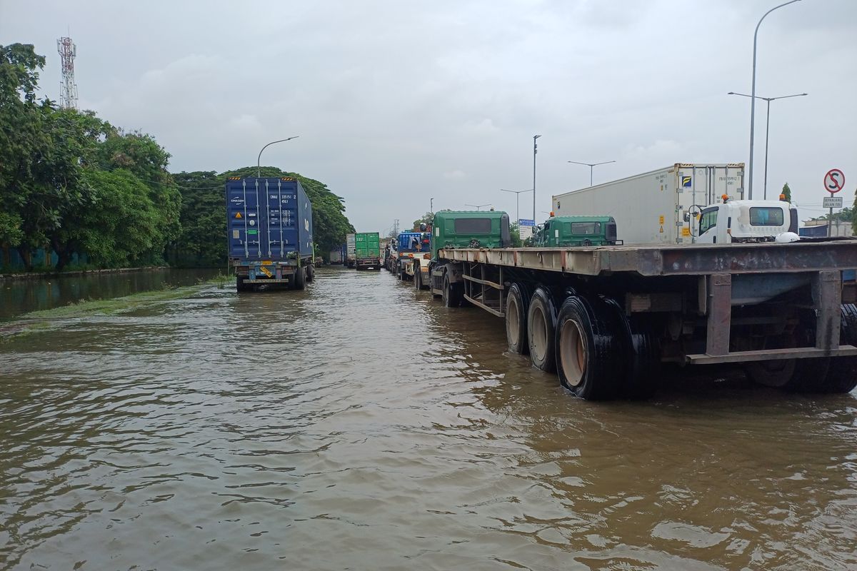 Genangan sisa banjir yang terjadi pada Minggu (18/1/2026) masih terlihat di Jalan Cakung Cilincing Raya, Jakarta Utara, Senin (19/1/2026)