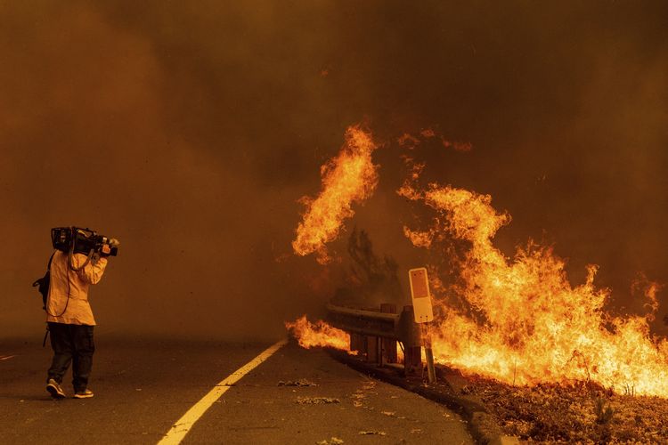 Seorang kameramen merekam api kebakaran hutan California yang meluber sampai jalan tol, pada Rabu (19/8/2020). Kebakaran ini salah satunya dipicu karena sambaran petir.
