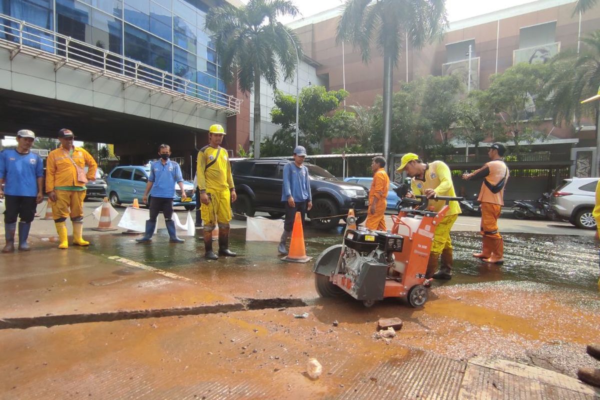 Petugas Suku Dinas Bina Marga Jakarta Selatan membelah aspal Jalan Metro Pondok Indah demi membuat saluran air sebagai solusi jangka pendek mengatasi genangan air, Jumat (17/3/2023) 